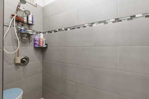 Bathroom featuring tiled shower and toilet