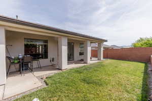 Rear view of property with stucco siding, a patio, and a fenced backyard
