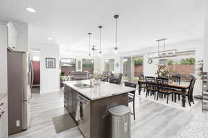 Kitchen with light stone countertops, open floor plan, stainless steel appliances, a kitchen bar, and dual tone cabinets