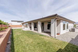 Back of property with a fenced backyard, stucco siding, and a patio area