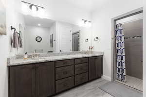 Full bathroom featuring double vanity and a stall shower