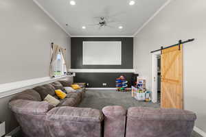 Cinema featuring a barn door, a ceiling fan, carpet, crown molding, and recessed lighting