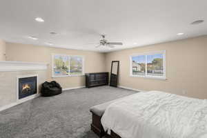 Bedroom featuring multiple windows, a glass covered fireplace, carpet flooring, a ceiling fan, and recessed lighting
