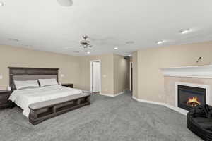 Carpeted bedroom with a ceiling fan, a high end fireplace, and recessed lighting