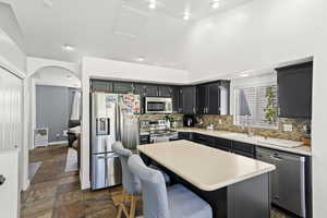 Kitchen with light countertops, lofted ceiling, stainless steel appliances, a center island, and dark cabinets