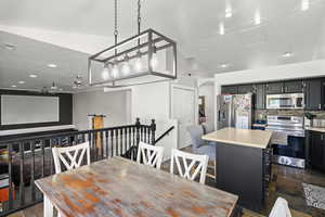 Dining area with vaulted ceiling, arched walkways, and recessed lighting