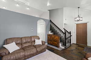 Living area with lofted ceiling, stone tile flooring, and arched walkways
