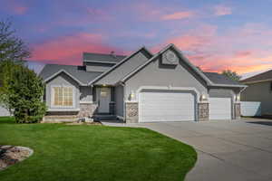 View of front of property featuring an attached garage, stucco siding, driveway, a front lawn, and brick siding