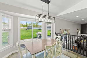 Dining room with ornamental molding, stone tile floors, vaulted ceiling, and recessed lighting