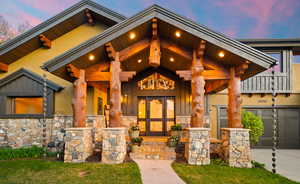 Property entrance with stone siding, stucco siding, and a porch