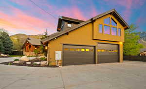 View of front facade with concrete driveway, stucco siding, a mountain view, and a garage