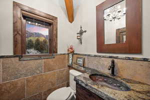Bathroom with vanity, tile walls, wainscoting, and suspended lighting
