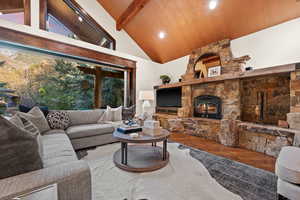 Living room with wood finished floors, lofted ceiling, a fireplace, and recessed lighting