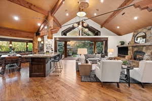 Living area featuring light wood finished floors, a stone fireplace, and suspended lighting