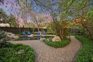 View of property's walkway and pond located inside fenced backyard