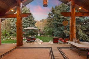 Deck at dusk featuring a patio, outdoor lounge area, and a lawn