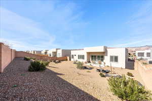 Back of house with a fenced backyard, a patio, stucco siding, and a mountain view