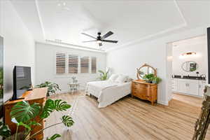 Bedroom featuring a raised ceiling, light wood-type flooring, a textured ceiling, and ceiling fan