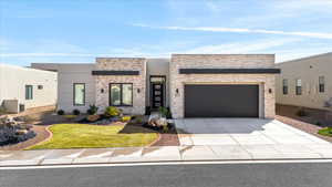 Modern home featuring a garage, concrete driveway, a front lawn, and stucco siding