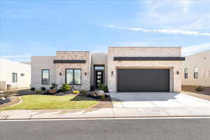 Contemporary home featuring driveway, an attached garage, stone siding, and stucco siding