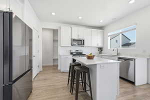 Kitchen featuring stainless steel appliances, white cabinets, and island