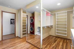 Walk in closet featuring light wood-style flooring and stacked washer and dryer