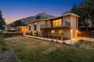 Back of property at dusk featuring brick siding, an attached garage, a mountain view, and concrete driveway