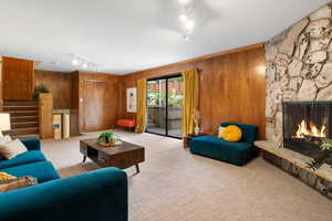 Carpeted living area with rail lighting, a fireplace, and wood walls