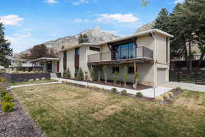 View of front of home featuring a mountain view, a garage, brick siding, driveway, and a balcony