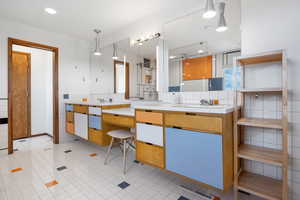 Full bathroom with tile walls, double vanity, a stall shower, and light tile patterned floors