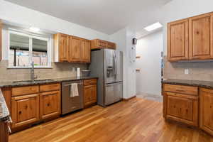 Kitchen featuring tasteful backsplash, dark stone counters, stainless steel appliances, and wood finish cabinets