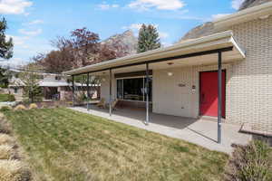 Back of house with a lawn, a patio, brick siding, and a mountain view