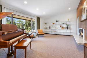 Sitting room with lofted ceiling, a high end fireplace, light carpet, and recessed lighting
