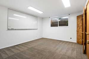 Unfurnished room with dark carpet and baseboards