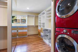 Laundry room with light wood finished floors and stacked washer / drying machine