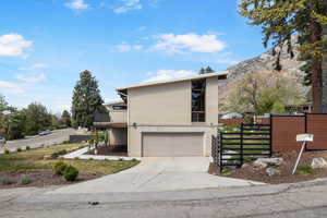 View of front of property with driveway, an attached garage, brick siding, and a gate
