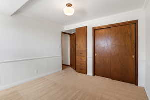 Unfurnished bedroom with a closet, ornamental molding, and light colored carpet