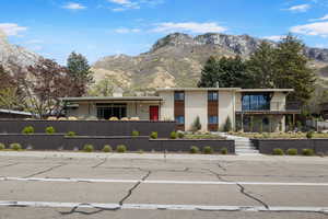 View of front facade featuring a mountain view, a chimney, brick siding, and a balcony