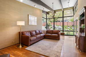 Living area with a chandelier, light wood-style floors, expansive windows, and beam ceiling