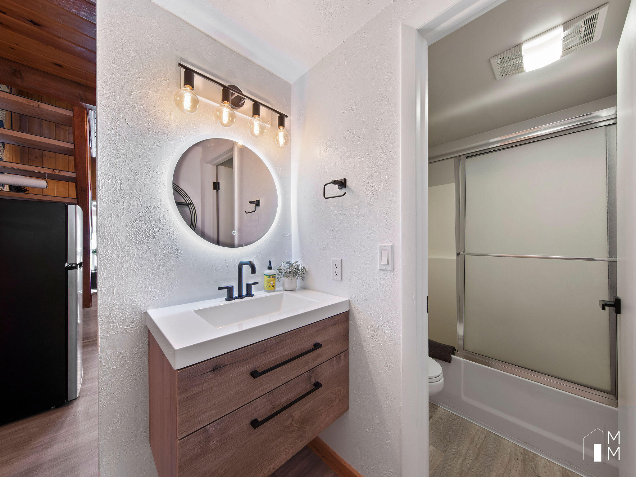 Full bath with a textured wall, vanity, shower / bath combination with glass door, and light wood-style floors