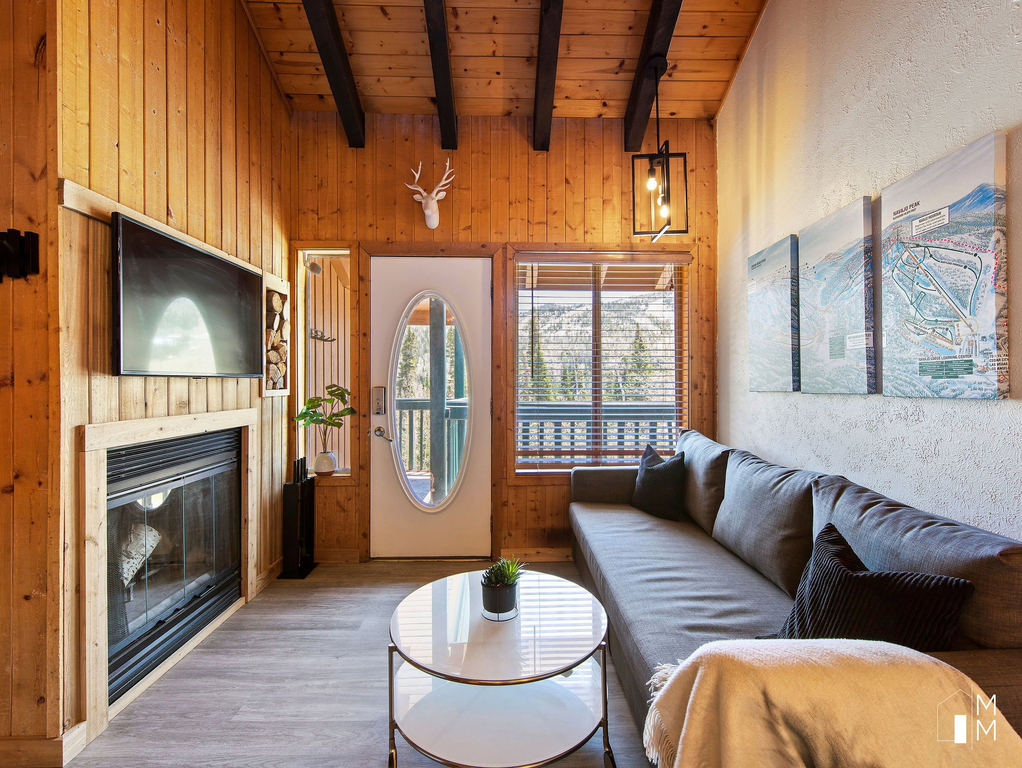Living room with wooden walls, a glass covered fireplace, wood finished floors, and a wood ceiling with exposed beams