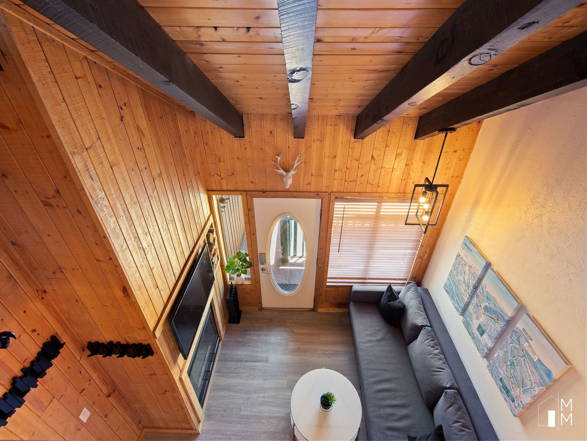 Living room with wooden walls, dark wood-style flooring, and a wooden ceiling with exposed beams