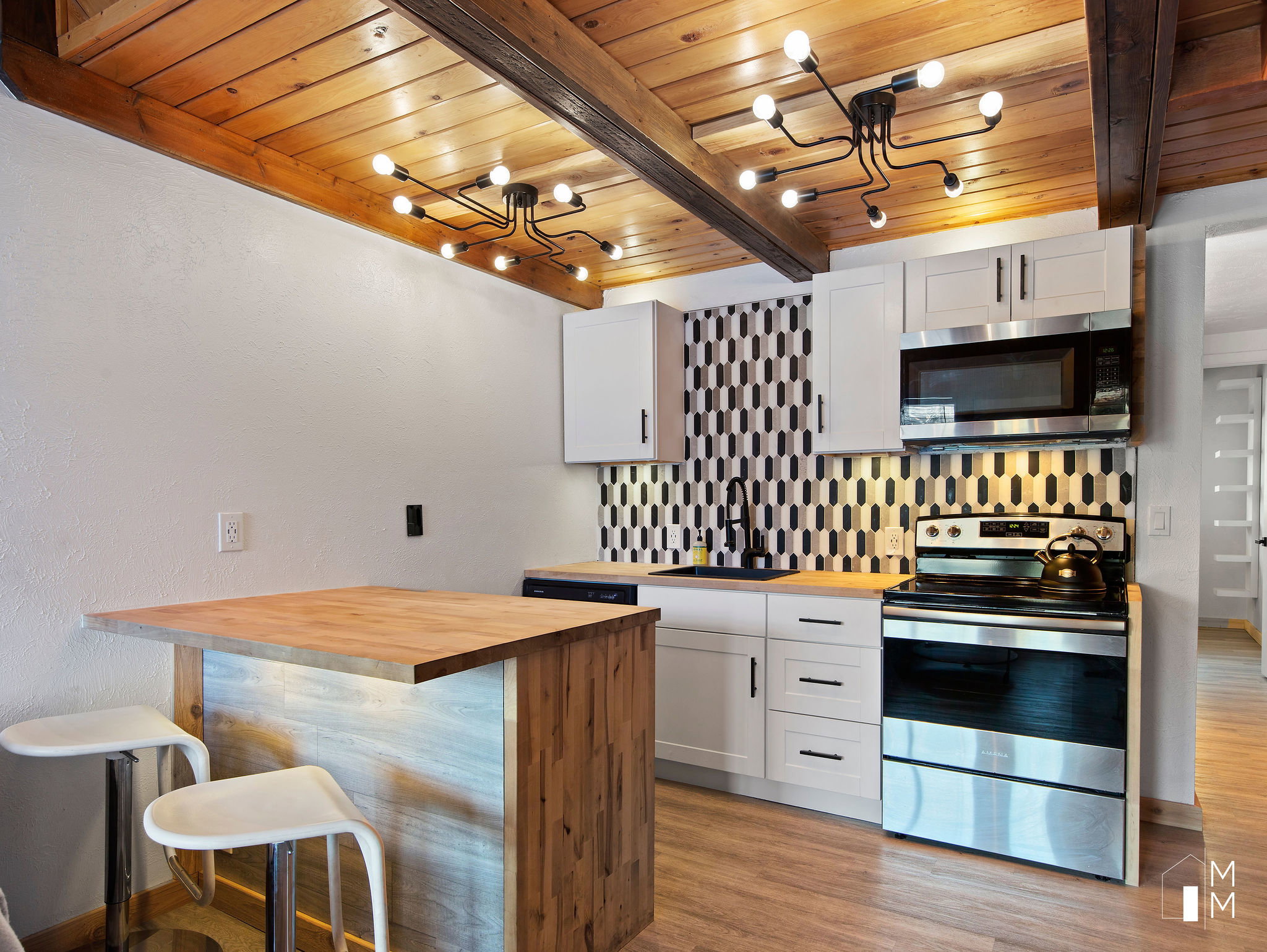 Kitchen with wooden counters, stainless steel appliances, a breakfast bar, tasteful backsplash, and white cabinets