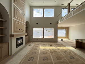 Unfurnished living room featuring a high ceiling and a glass covered fireplace