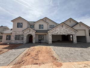 View of front of property with stucco siding, decorative driveway, an attached garage, stone siding, and a tiled roof