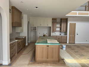 Kitchen with a center island, backsplash, arched walkways, and two tone cabinetry