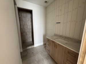 Bathroom with vanity, light tile patterned flooring, and an accent wall