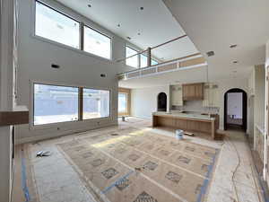 Unfurnished living room with arched walkways and a high ceiling