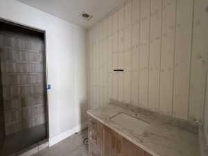 Full bath featuring vanity, light tile patterned floors, and a walk in shower