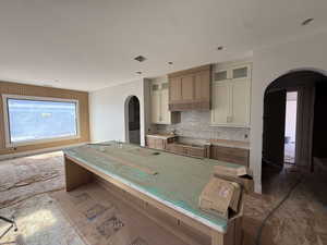Two tone kitchen featuring arched walkways, glass insert cabinets, dual tone cabinets, a center island, and decorative backsplash
